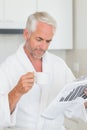 Happy man reading newspaper at breakfast in a bathrobe Royalty Free Stock Photo