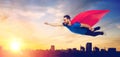 Happy man in red superhero cape flying over city Royalty Free Stock Photo