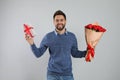 Happy man with red tulip bouquet and gift box on light grey background. 8th of March celebration Royalty Free Stock Photo