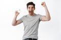 Happy man rejoicing, showing credit card and scream of joy and excitement, celebrating win, standing over white Royalty Free Stock Photo