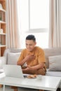 Happy man relaxing on couch while video calling using laptop at home Royalty Free Stock Photo