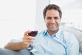 Happy man relaxing on sofa with glass of red wine Royalty Free Stock Photo