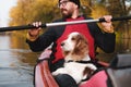 Happy man rowing a canoe with his spaniel dog, sunny autumn weather. Royalty Free Stock Photo