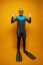 Happy man scuba diver in diving mask showing okay sign on yellow studio wall background Royalty Free Stock Photo