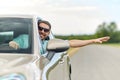 Happy man in shades driving car and waving hand