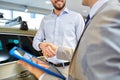 Happy man shaking hands in auto show or salon Royalty Free Stock Photo