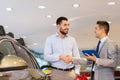 Happy man shaking hands in auto show or salon Royalty Free Stock Photo