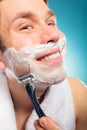 Happy man shaving using razor with cream foam. Royalty Free Stock Photo