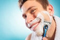 Happy man shaving using razor with cream foam. Royalty Free Stock Photo