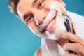 Happy man shaving using razor with cream foam. Royalty Free Stock Photo