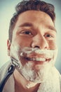 Happy man shaving using razor with cream foam. Royalty Free Stock Photo