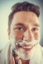 Happy man shaving using razor with cream foam. Royalty Free Stock Photo