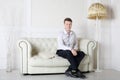 Happy man in shirt and pants sits on white leather sofa Royalty Free Stock Photo