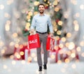 Happy man with shopping bags over christmas lights Royalty Free Stock Photo