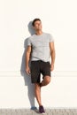 Happy man in shorts leaning against white wall Royalty Free Stock Photo