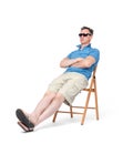 Happy man in shorts, t-shirt, sunglasses is resting on a chair on the beach, isolated on white background Royalty Free Stock Photo