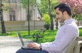 Happy man sitting on bench and using laptop Royalty Free Stock Photo
