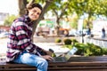 Happy man sitting on bench and using laptop in a park. Young man sitting on the park bench with laptop Royalty Free Stock Photo