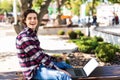 Happy man sitting on bench and using laptop in a park. Young man sitting on the park bench with laptop Royalty Free Stock Photo