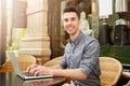 Happy man sitting at cafe working on laptop outside Royalty Free Stock Photo