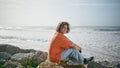 Happy man sitting coast beautiful summer day. Guy traveler relaxing on beach Royalty Free Stock Photo