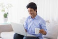 Happy man sitting on couch using laptop having coffee Royalty Free Stock Photo