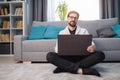 Happy man sitting on floor with laptop at home Royalty Free Stock Photo