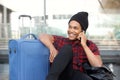 Happy man sitting on floor at station with travel bags and talking with mobile phone Royalty Free Stock Photo