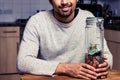 Happy man sitting in kitchen with piggy bank Royalty Free Stock Photo