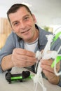 Happy man smiling at camera while fixing crashed drone Royalty Free Stock Photo