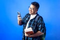 Happy Indian college student using mobile phone with books on hi Royalty Free Stock Photo