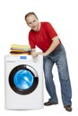 Happy man smiling standing next to a new washing machine and a stack of clean laundry Royalty Free Stock Photo