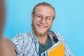 Happy man student blogger take selfie on blue background, phone camera view.