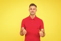 Happy man with stylish beard hair in red tshirt show thumbs ups satisfactory hand gesture yellow background