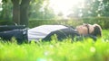 Happy man in suit lying on grass and enjoying sunny day, harmony with nature
