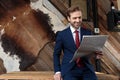 Happy man in suit smiling and reading newspaper