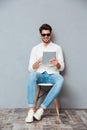 Happy man in sunglasses sitting on chair and using tablet Royalty Free Stock Photo