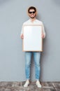 Happy man in sunglasses standing and holding blank white board Royalty Free Stock Photo