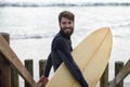 Happy man, surfer and beach by waves for fitness, exercise or extreme sports on outdoor shore. Young male person with Royalty Free Stock Photo