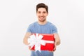 Happy man in t-shirt giving gift and looking at camera