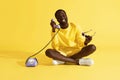 Happy man talking on purple phone sitting on yellow background