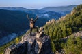 Happy man traveller standing with raised hands on mountain top and celebrating success. Royalty Free Stock Photo