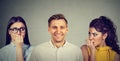 Happy man and two insecure women anxiously looking at him Royalty Free Stock Photo