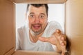 Happy man unpacking, opening carton box and looking inside. Man smiling unpacking and carton box
