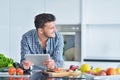 Happy man using digital tablet in kitchen at home Royalty Free Stock Photo