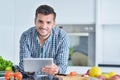 Happy man using digital tablet in kitchen at home Royalty Free Stock Photo