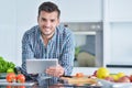 Happy man using digital tablet in kitchen at home Royalty Free Stock Photo