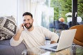 Happy man using mobile phone and laptop while in the living room at home Royalty Free Stock Photo