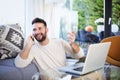 Happy man using mobile phone and laptop while sitting in the sitting room at home Royalty Free Stock Photo