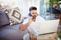 Happy man using mobile phone and laptop while sitting in the sitting room at home Royalty Free Stock Photo